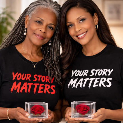 Two women wearing 'Your Story Matters' shirts holding red roses in glass boxes.